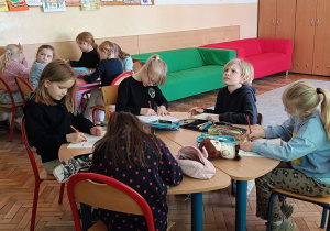 Uczniowie wykonują przy stoliku ćwiczenie plastyczne