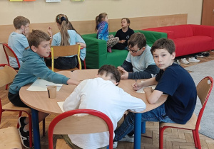 Dzieci wykonują ćwiczenie kreatywne przy stolikach
