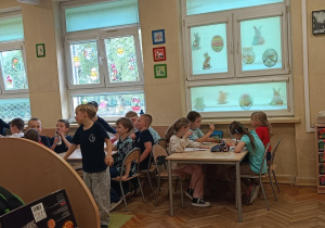 Dzieci przy stolikach wykonują twórcze ćwiczenie na myślenie