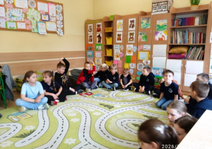 Uczniowie siedzą na dywanie