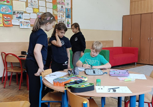 Dzieci wykonują przy stoliku ćwiczenie plastyczne