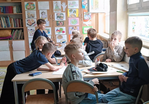 Dzieci przy stolikach współpracują podczas zajęć