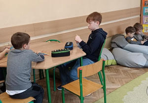 Uczniowie przy stoliku współpracują ze sobą podczas zajęć