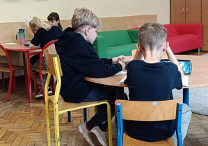 Dzieci przy stoliku wykonują ćwiczenie kreatywne wspólnie