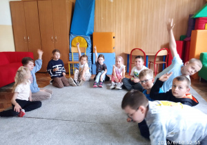 Uczniowie siedzą na dywanie