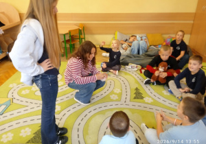 Uczniowie siedzą na dywanie