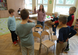 Uczniowie stoją przy krzesełkach
