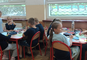 Dzieci tworzą pracę tematyczną dotyczącą pozdrowień dla sąsiadów