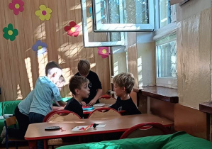 Dzieci pracują przy stoliku wykonując ćwiczenie plastyczne