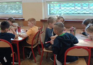 Uczniowie przy stolikach eykonują prace