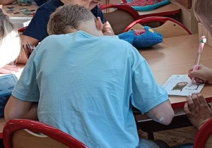 Dzieci współpracują ze sobą przy stoliku wykonując ćwiczenie na kreatywność