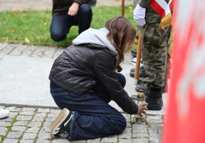 Uczennica składa kwiaty