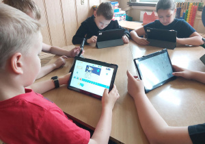 Uczniowie pracują na tabletach, tworzą aplikację w programie Scratch Junior.