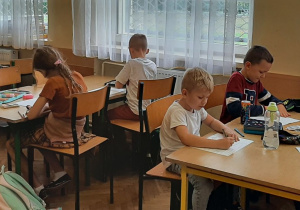 Uczniowie siedzą przy stolikach
