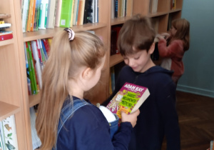 Uczniowie w bibliotece szkolnej z książkami