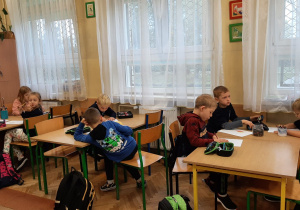 Uczniowie siedzą przy stolikach
