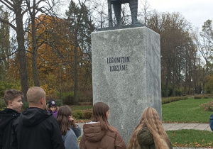 Uczniowie stoją przed pomnikiem